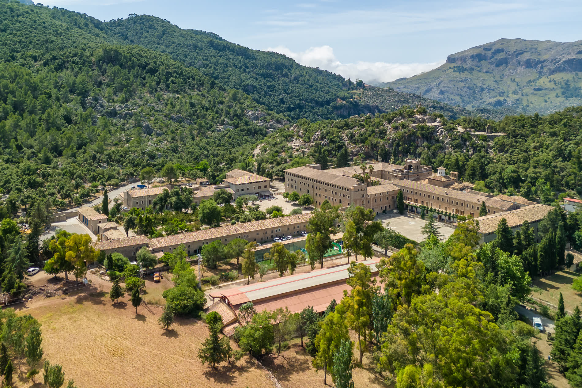 Luftbild einer großen Klosteranlage mit Innenhöfen zwischen bewaldeten Bergen